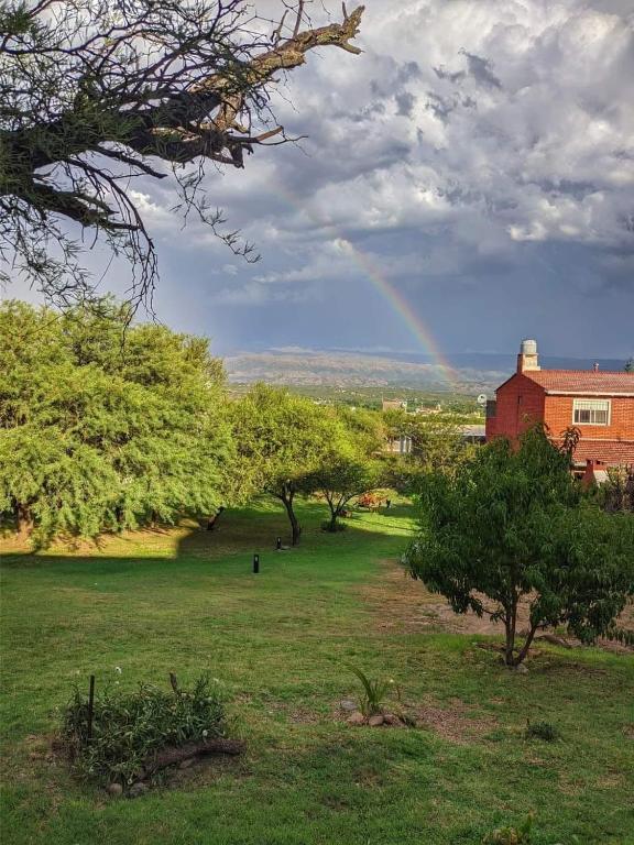 a rainbow over a field with trees and a building at Casas de campo Traslasierra in Villa Cura Brochero