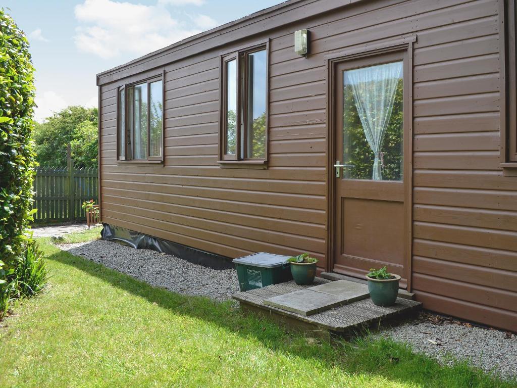 a wooden cabin with a door and two potted plants at Heather Brae Lodge in Nancledra