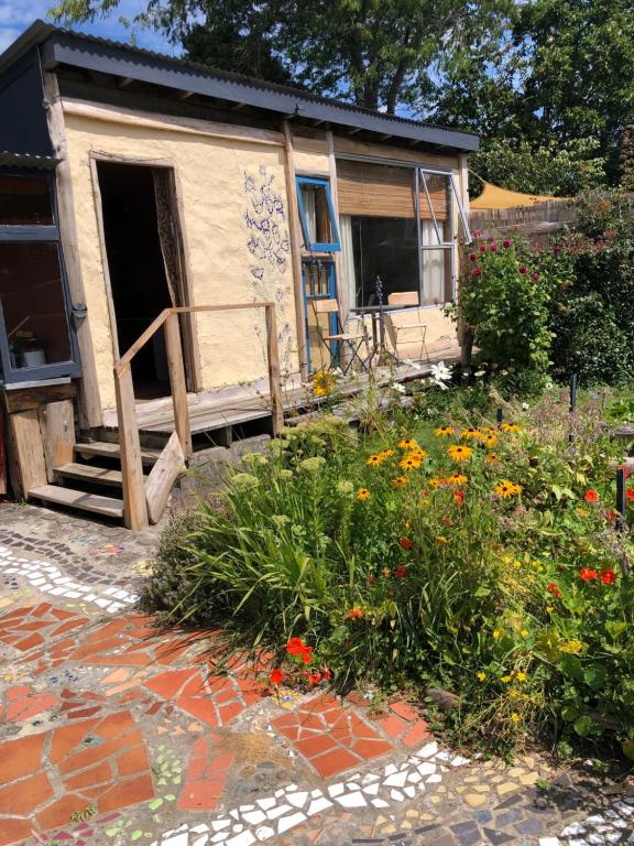a house with a garden with flowers in front of it at Dragon's Den - self contained unit in Takaka