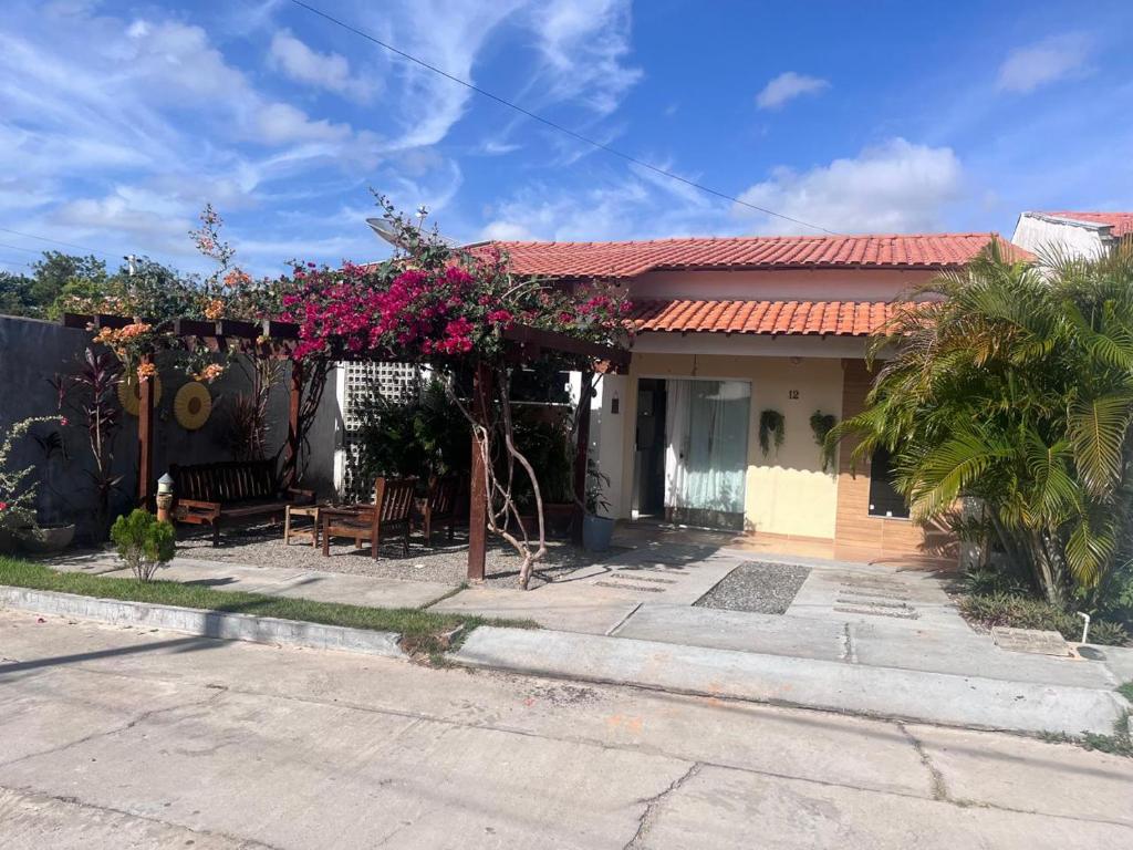 a house with a pergola with pink flowers on it at Casa Temporada Peter in Tutóia