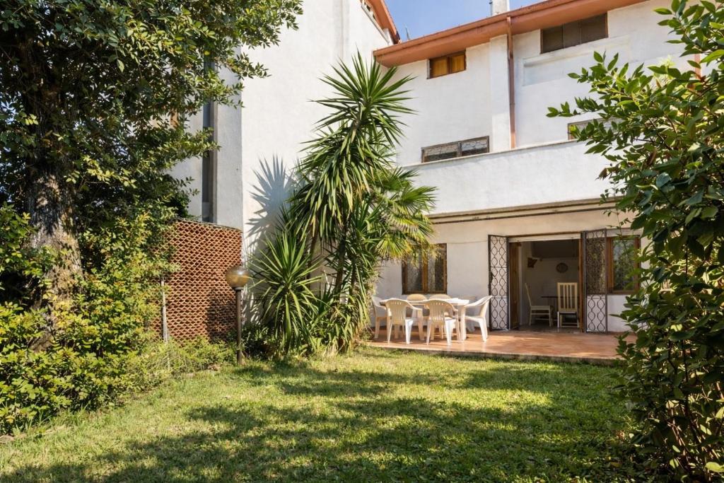 a backyard of a house with a table and chairs at Villa summertime walking distance from the sea with garden in Fregene