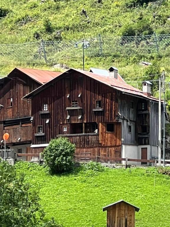 an old wooden barn with a green field next to it at Vicinanza d'Andraz in Andraz