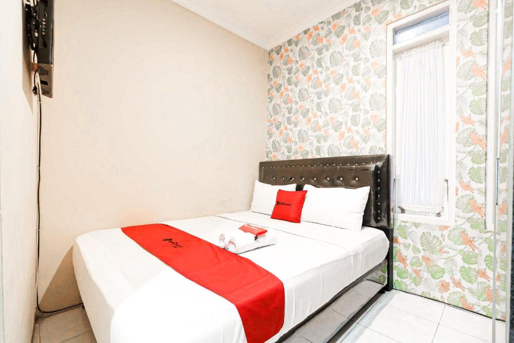 a bedroom with a bed with a red blanket on it at RedDoorz Syariah Near Jam Gadang Bukit tinggi 2 in Bukittinggi