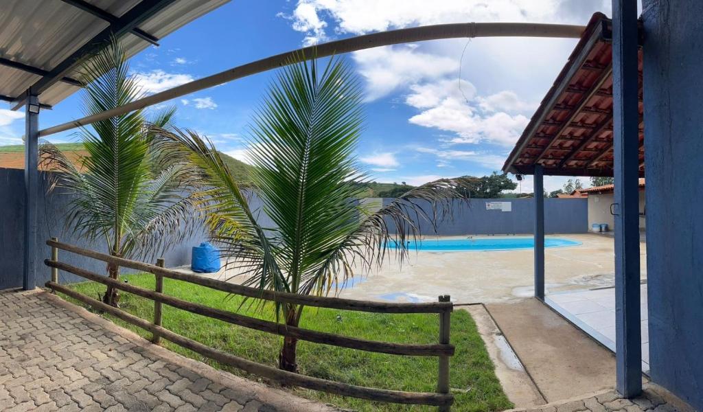 a palm tree next to a fence next to a swimming pool at Rancho do Tomate in São Roque de Minas