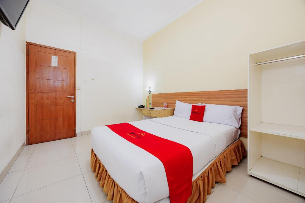 a bedroom with a large bed with a red and white blanket at RedDoorz Plus at Amalio Hotel Surapati in Bandung