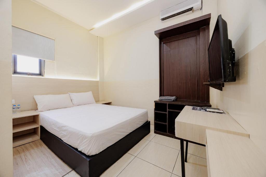 a small room with a bed and a television at Hotel C18 at Cibaduyut Mitra RedDoorz in Bandung