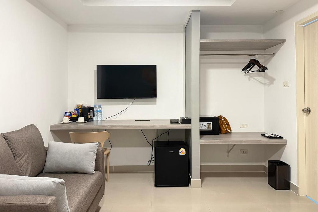 The room’s desk and storage wall, with a television, refreshments, refrigerator, and open wardrobe.