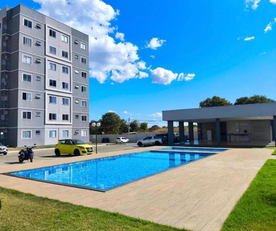 a building with a swimming pool in front of a building at Brisas do Lago 2 Quartos in Palmas