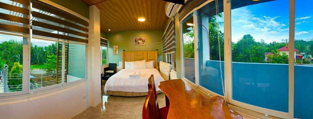 a bedroom with a bed and a balcony with windows at TUBURAN Poolside in Nagsulang