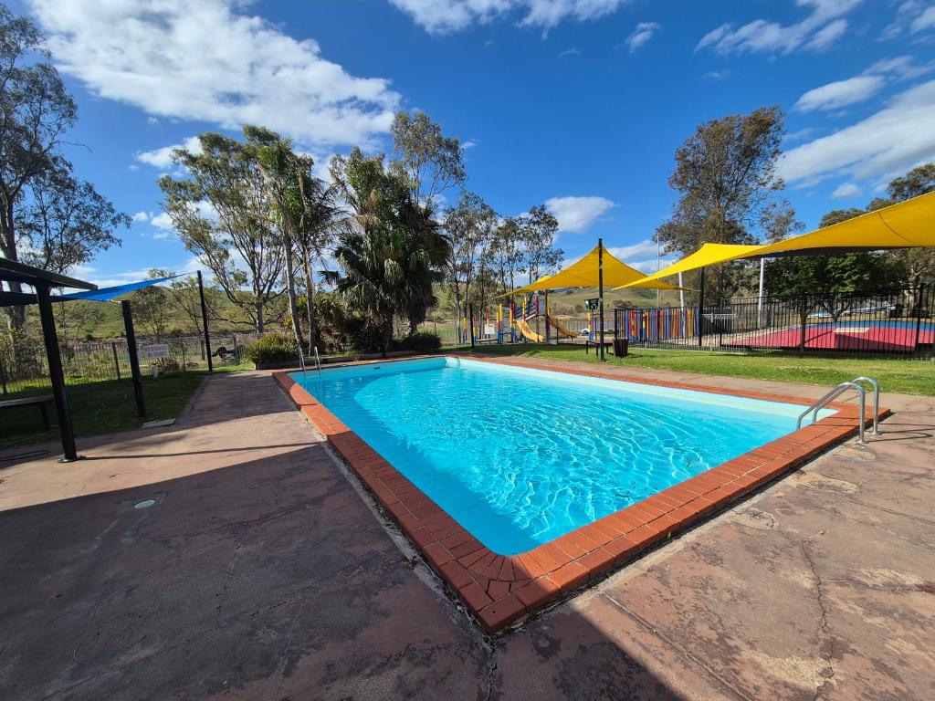a swimming pool with a playground and yellow umbrellas at Bonnie Doon Caravan Park in Bonnie Doon