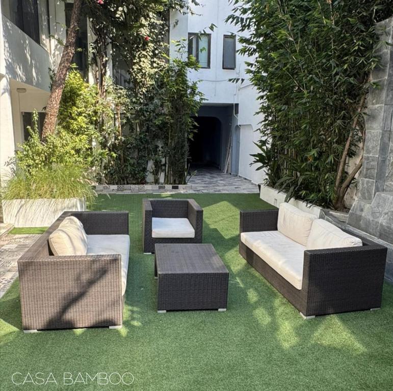 a patio with chairs and couches on grass at Casa Bamboo in Mexico City