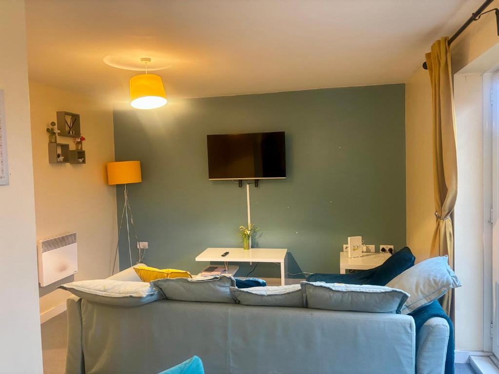 a living room with a blue couch and a flat screen tv at Peaceful Urban Retreat in Wolverhampton city in Wolverhampton