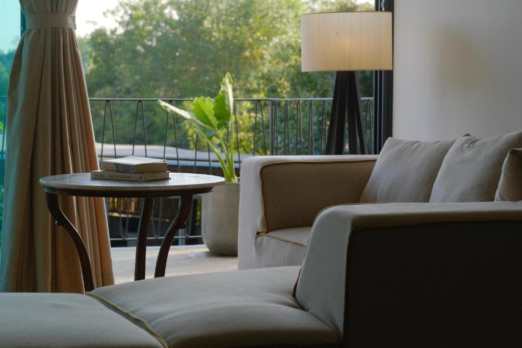 a living room with a couch and a table and a balcony at Turiya Retreat in Auroville