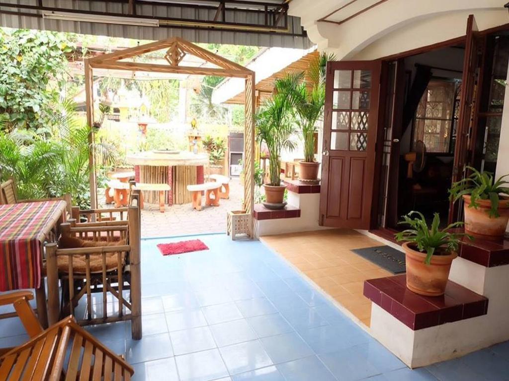 an open patio with a table and potted plants at Hug Glur House Tour and Hostel in Chiang Mai