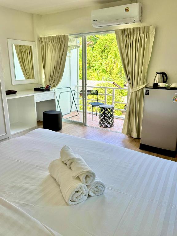 a white bed with a pile of towels on it at Top Residence Patong in Patong Beach