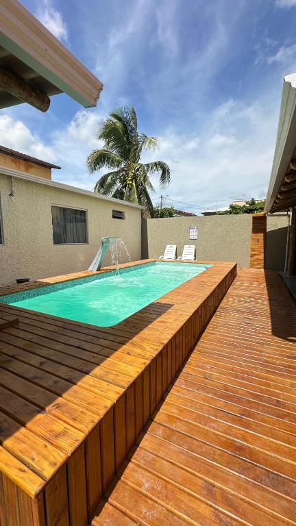 a swimming pool with a wooden deck next to a house at Duplex 2 Suites Pool Barbecue Air in Santa Cruz Cabrália