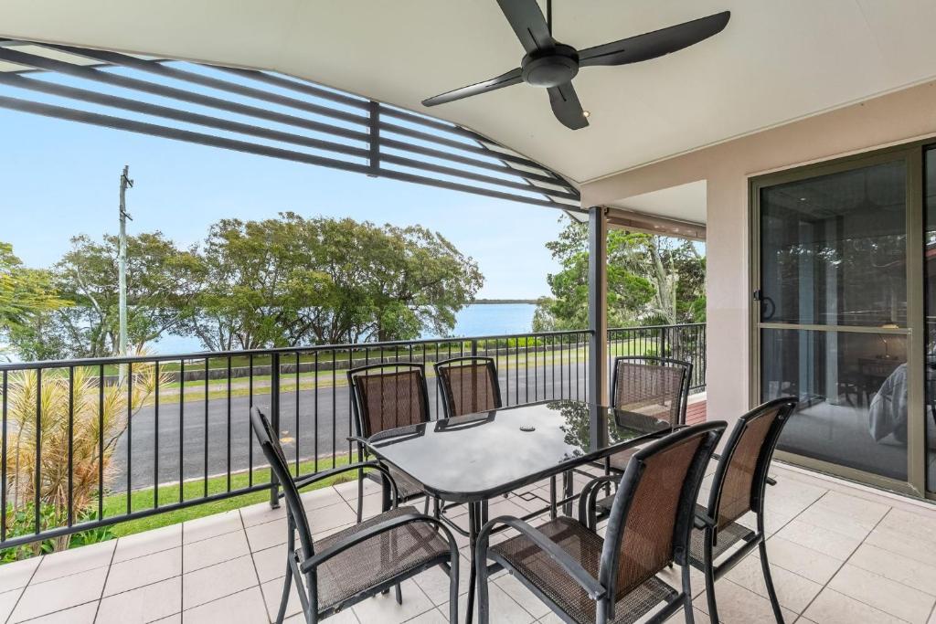 a patio with a table and chairs on a balcony at Amarco Spacious Riverfront with Sunset Views in Iluka