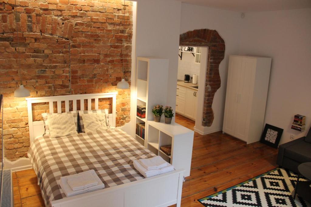 - une chambre avec un lit et un mur en briques dans l'établissement Apartament z patio w centrum Starego Miasta, à Toruń