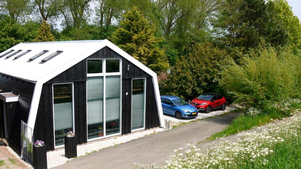 eine schwarz-weiße Garage mit Autos auf einem Parkplatz in der Unterkunft Markermeerlogies in Bovenkarspel