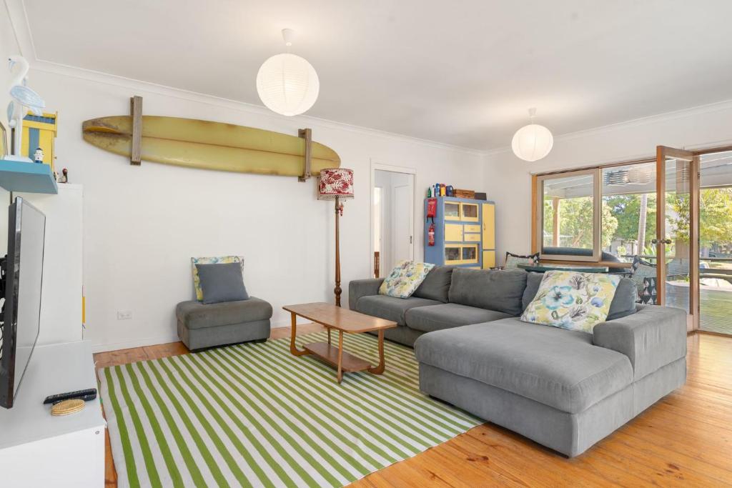 a living room with a couch and a surfboard on the wall at Pet Friendly Island Garden Retreat in Cowes in Cowes