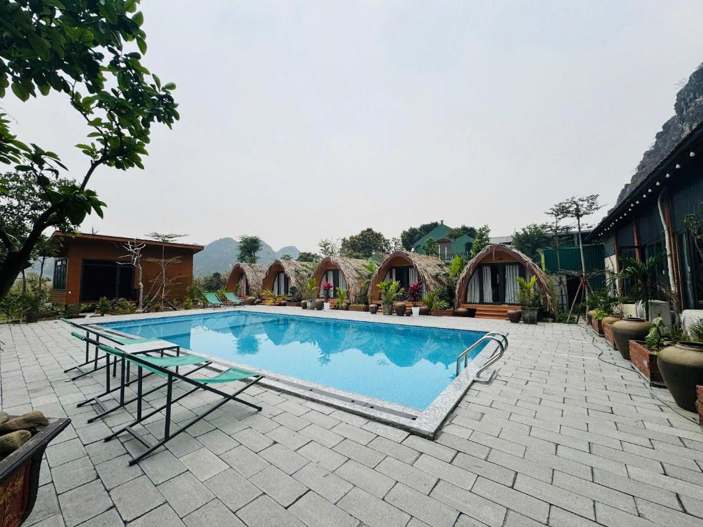 a large swimming pool with a table and chairs in a yard at Bình An Mountain Side Bungalow in Nguyên Ngoại