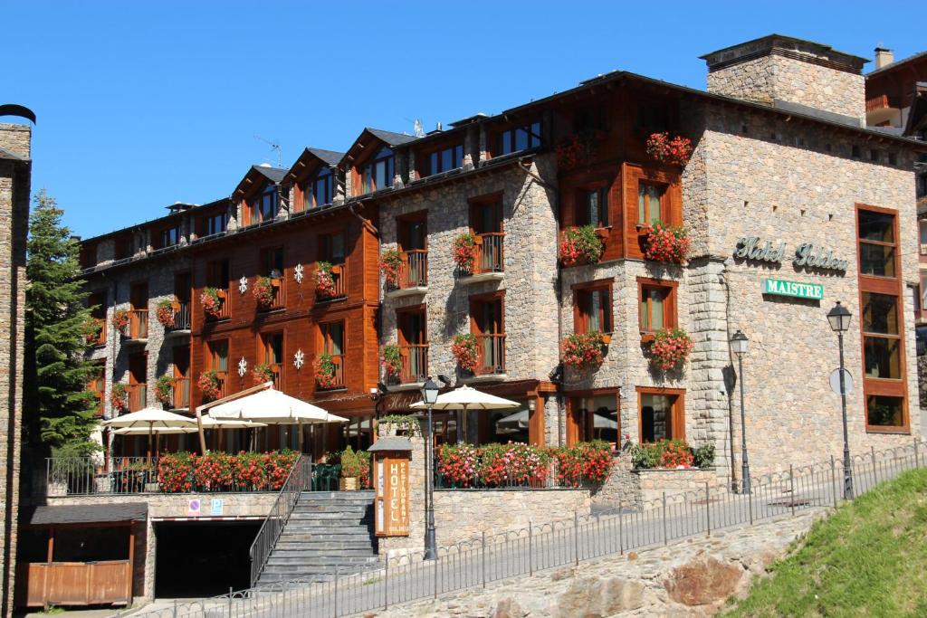 un grand bâtiment avec des parasols en face de celui-ci dans l'établissement Hotel Soldeu Maistre, à Soldeu