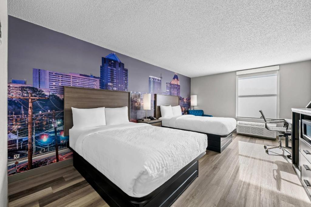 a hotel room with two beds and a tv at Clarion Pointe I-85 High Point - Archdale in Westwood