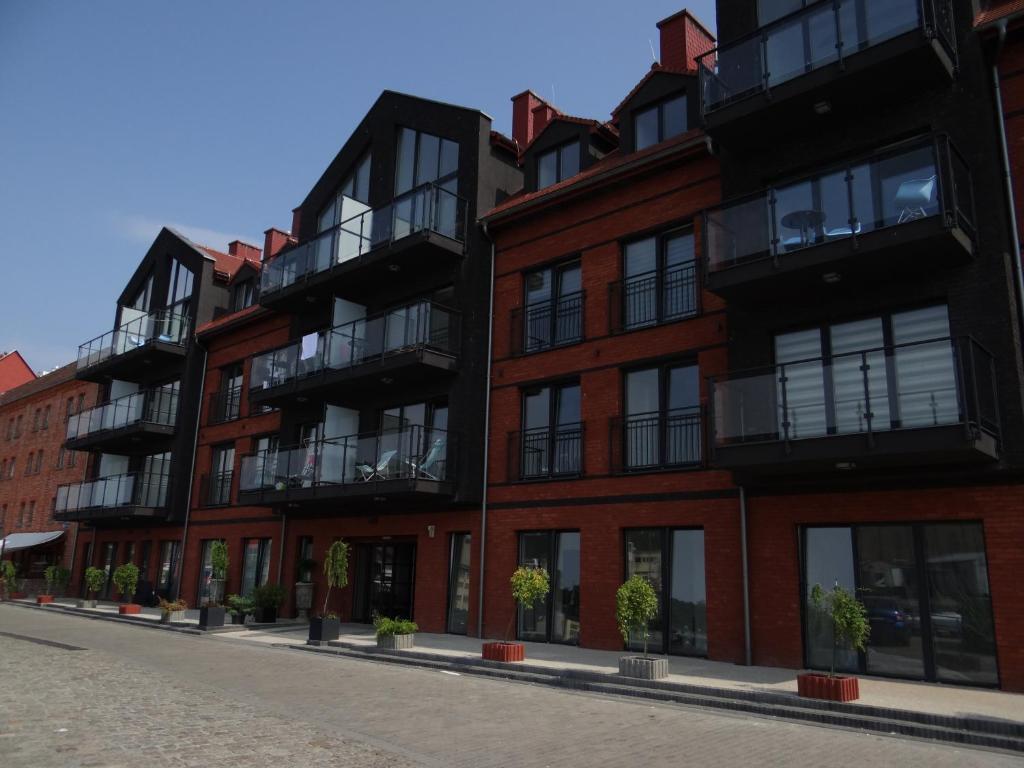 un edificio in mattoni rossi con balconi su una strada di Apartament Portowy w Ustce a Ustka