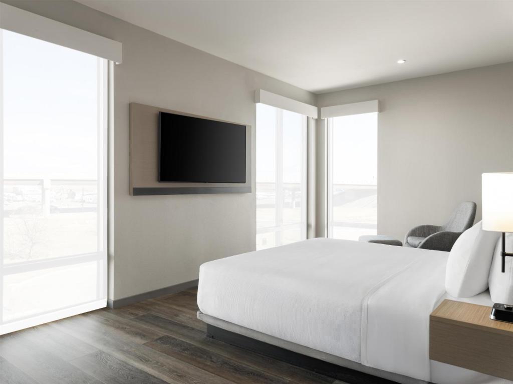 a white bedroom with a bed and a flat screen tv at Hyatt Place Casper in Casper