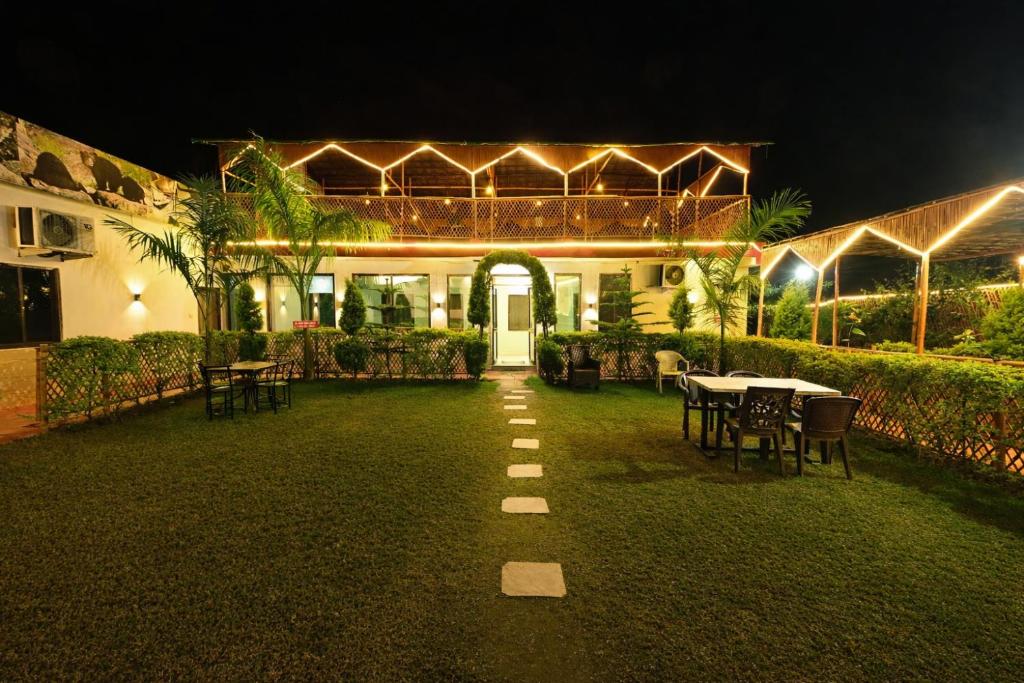 a house with a patio with tables and chairs at night at Hotel Happy Forest -Boutique Garden Retreat in Mount Abu in Mount Ābu