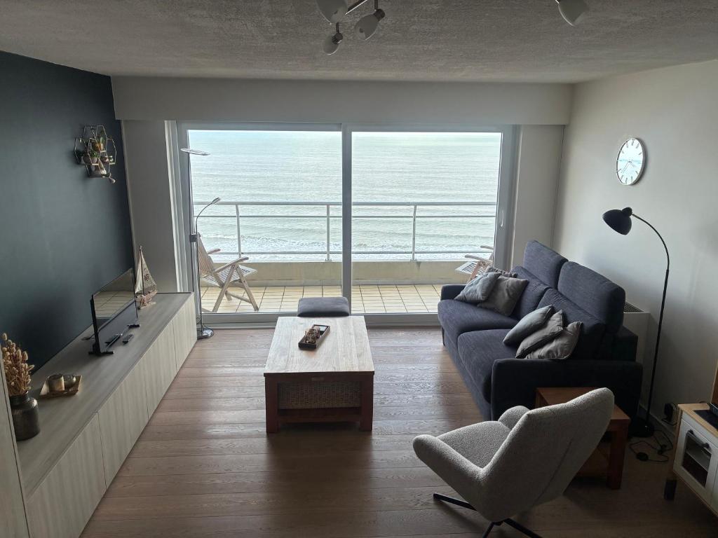a living room with a blue couch and a view of the ocean at Golden Sun in Middelkerke