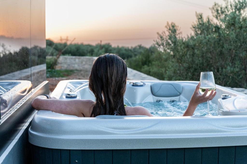 a woman in a bath tub with a glass of wine at Dias Guest House in Rethymno