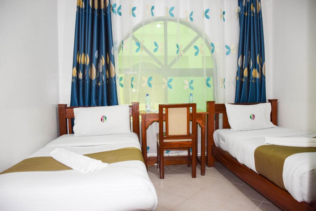 a room with two beds and a table and a window at Comfy Inn Hotel in Eldoret
