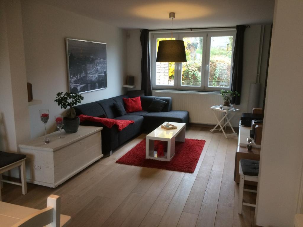 La Petite Villa في سبا: غرفة معيشة مع أريكة زرقاء وسجادة حمراء