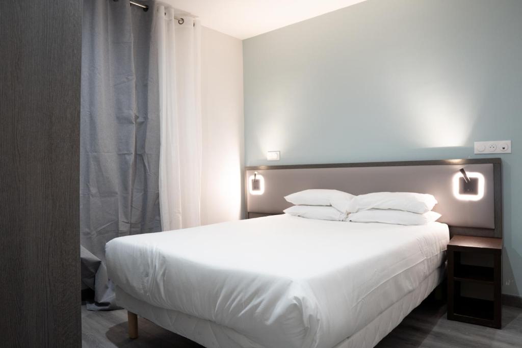 a bedroom with a bed with white sheets and pillows at Aero Hotel in Issy-les-Moulineaux