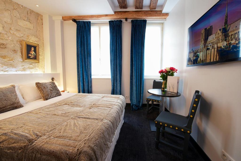 
a hotel room with a bed, table, and window at Hôtel le Clos de Notre Dame in Paris
