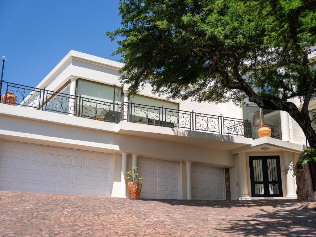 a white house with a balcony on top of it at Oniro Guest House in Bedfordview