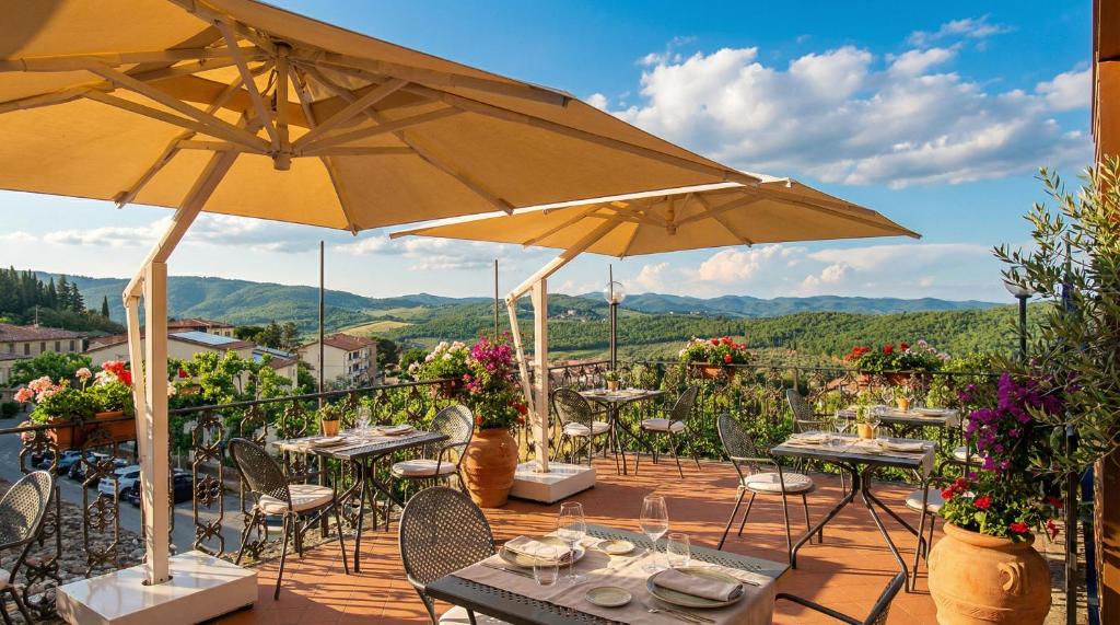 a patio with tables and chairs and umbrellas at Palazzo Leopoldo Dimora Storica & Spa in Radda in Chianti