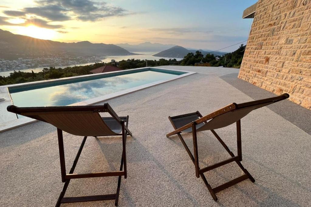 a pair of chairs sitting on a patio with a swimming pool at Bay View Village - Villa Eléanore 1 in MitroviÄ‡i