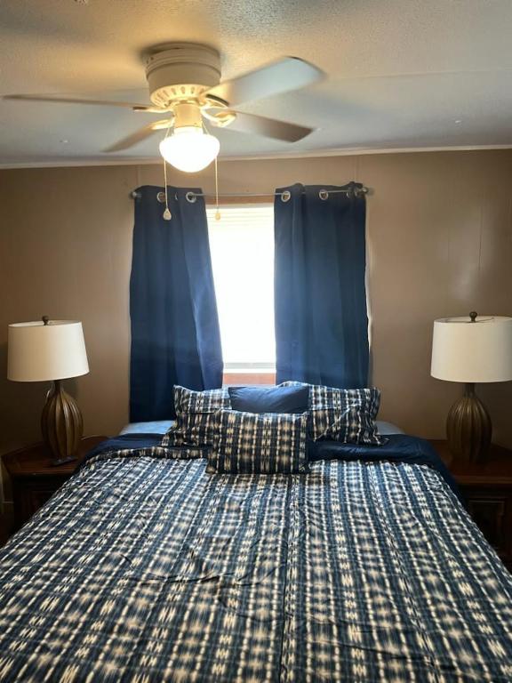 a bedroom with a bed with blue curtains and a ceiling fan at Mem's Place in Bluefield