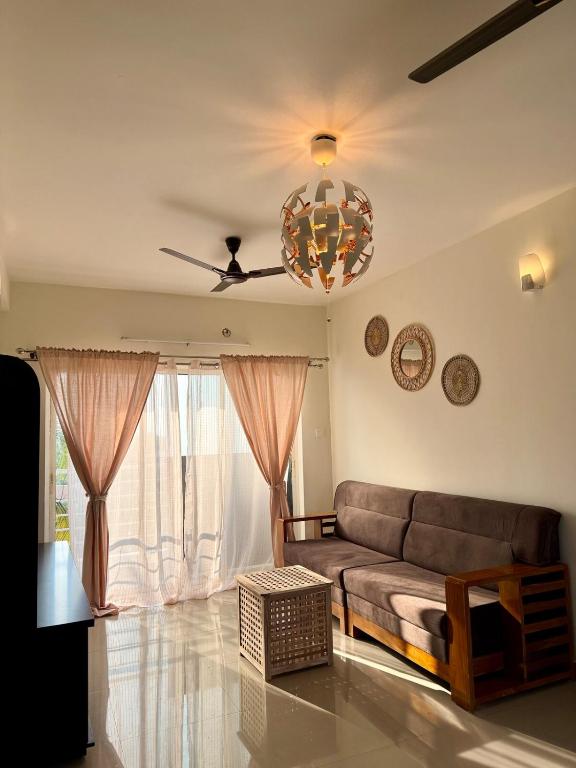 a living room with a couch and a ceiling fan at Between Tides nd Toasts Udupi Manipal in Manipal