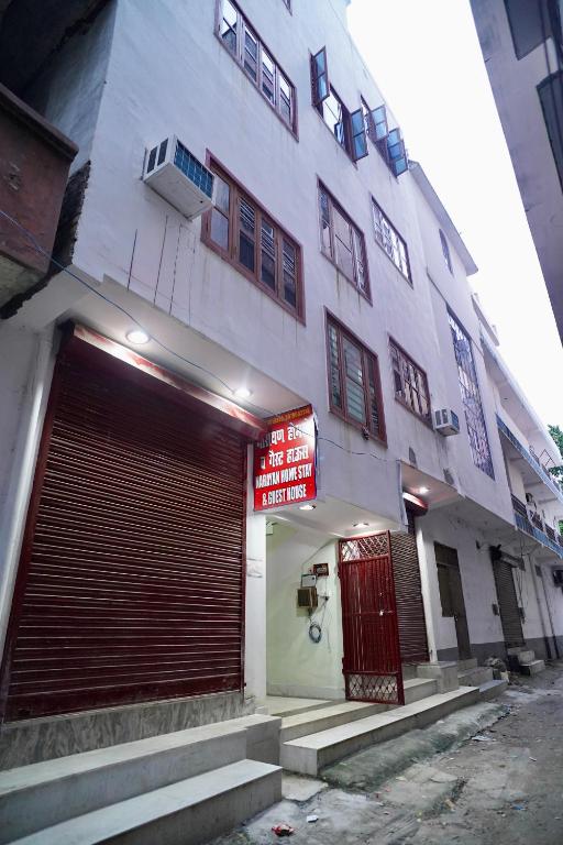 a large white building with a garage in front of it at Narayan Homestay & Guest House in Haridwār