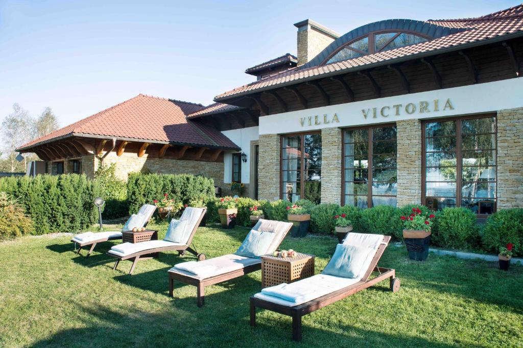 a group of chairs sitting in the grass in front of a building at Villa Victoria in Rydzewo