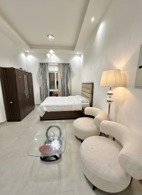 a bedroom with a bed and two chairs and a table at Entire Studio Apartment with King Bed in Ajman 