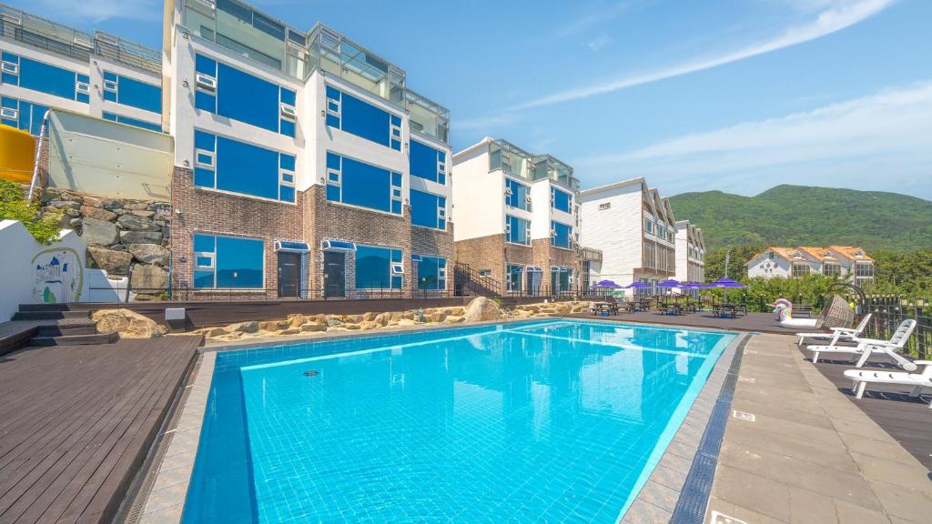 a swimming pool in front of a building at Geoje Badageurigo Pension in Geoje