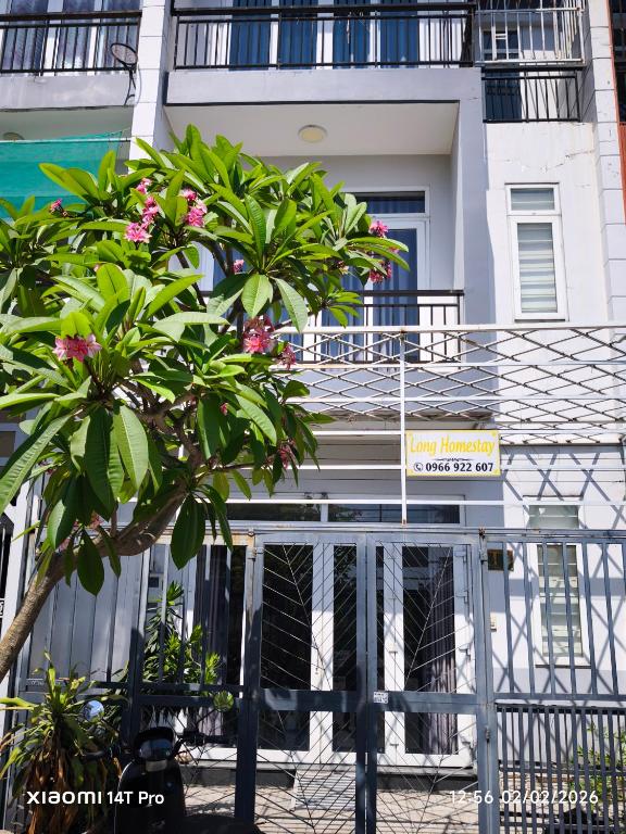 a tree with pink flowers in front of a building at Long Homestay Phuc An in Ðức Hòa