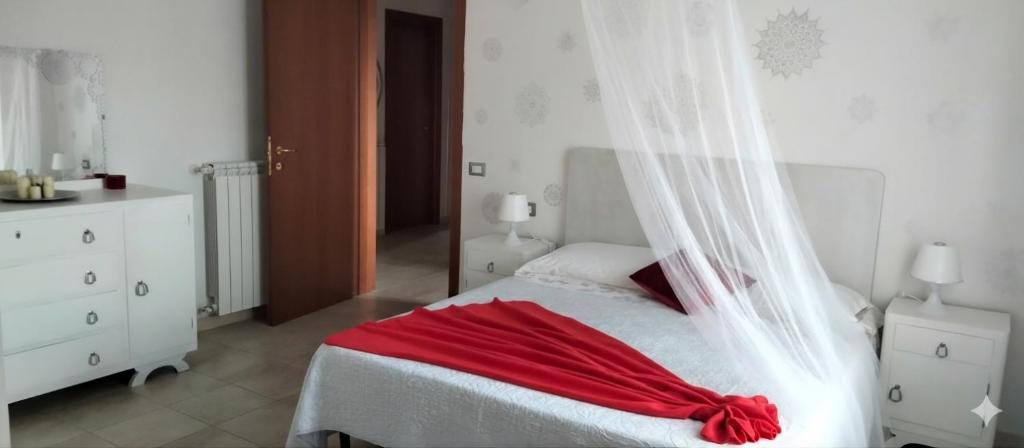 a white bedroom with a red blanket on a bed at Casa Effe in Cecina