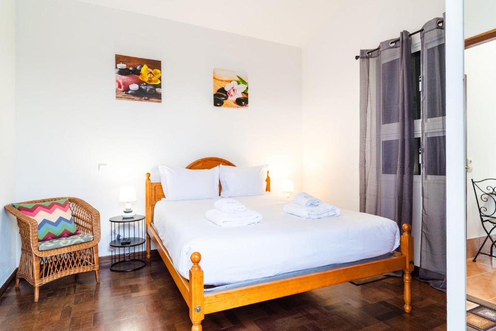 a bedroom with a bed and a chair at GuestReady - Funchal Hideaway with BBQ in Funchal