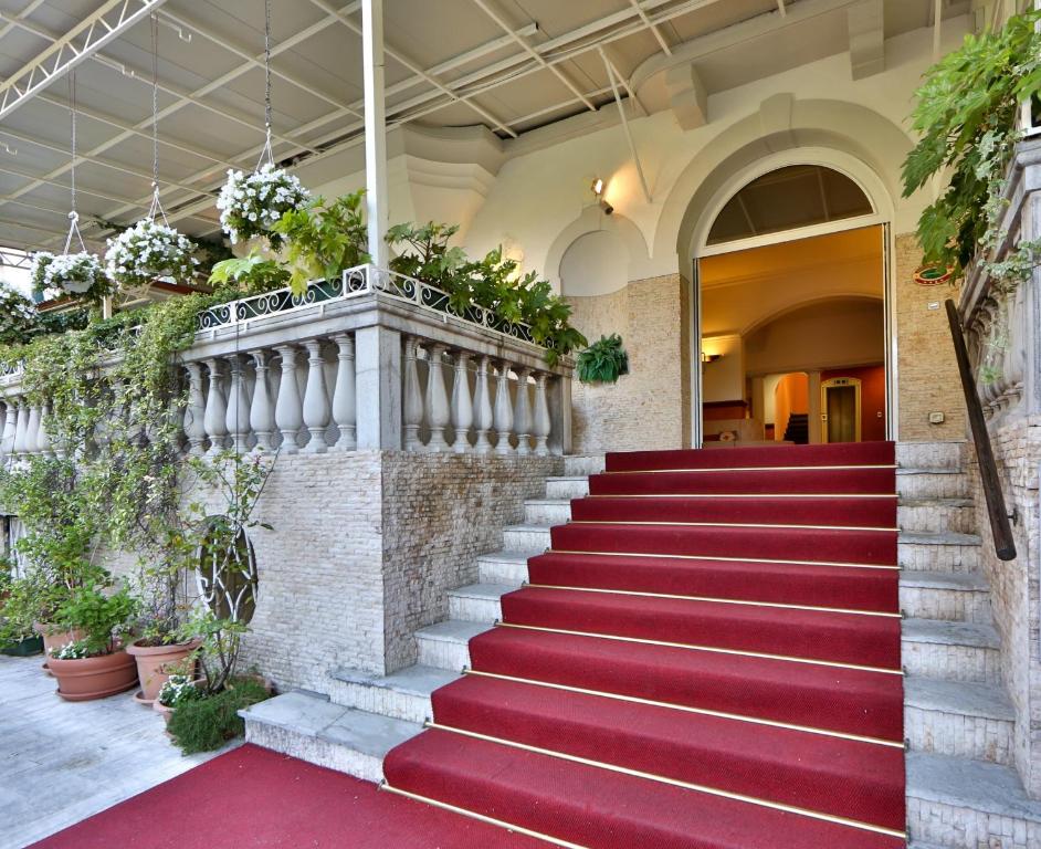 a red carpeted staircase in a building with plants at Hotel Biasutti in Venice-Lido