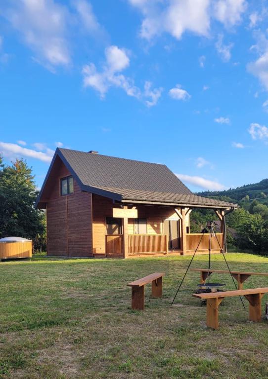 a log cabin with a swing and a house at Domek w Zabrzeży in Łącko